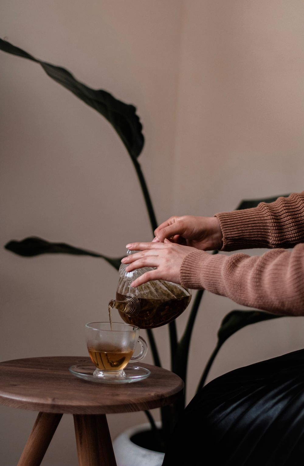 Tea being poured from a glass teapot into a cup
