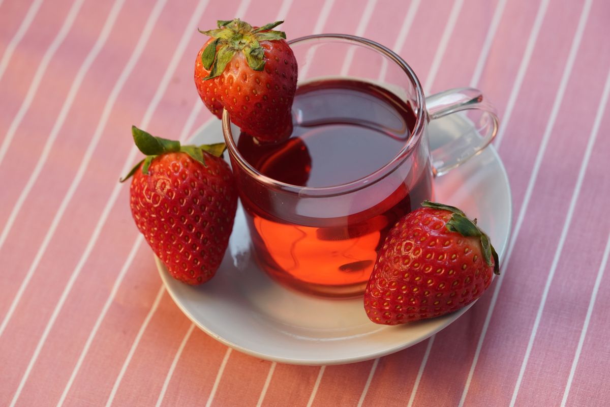 Strawberry tea with fresh berries on a pink striped cloth