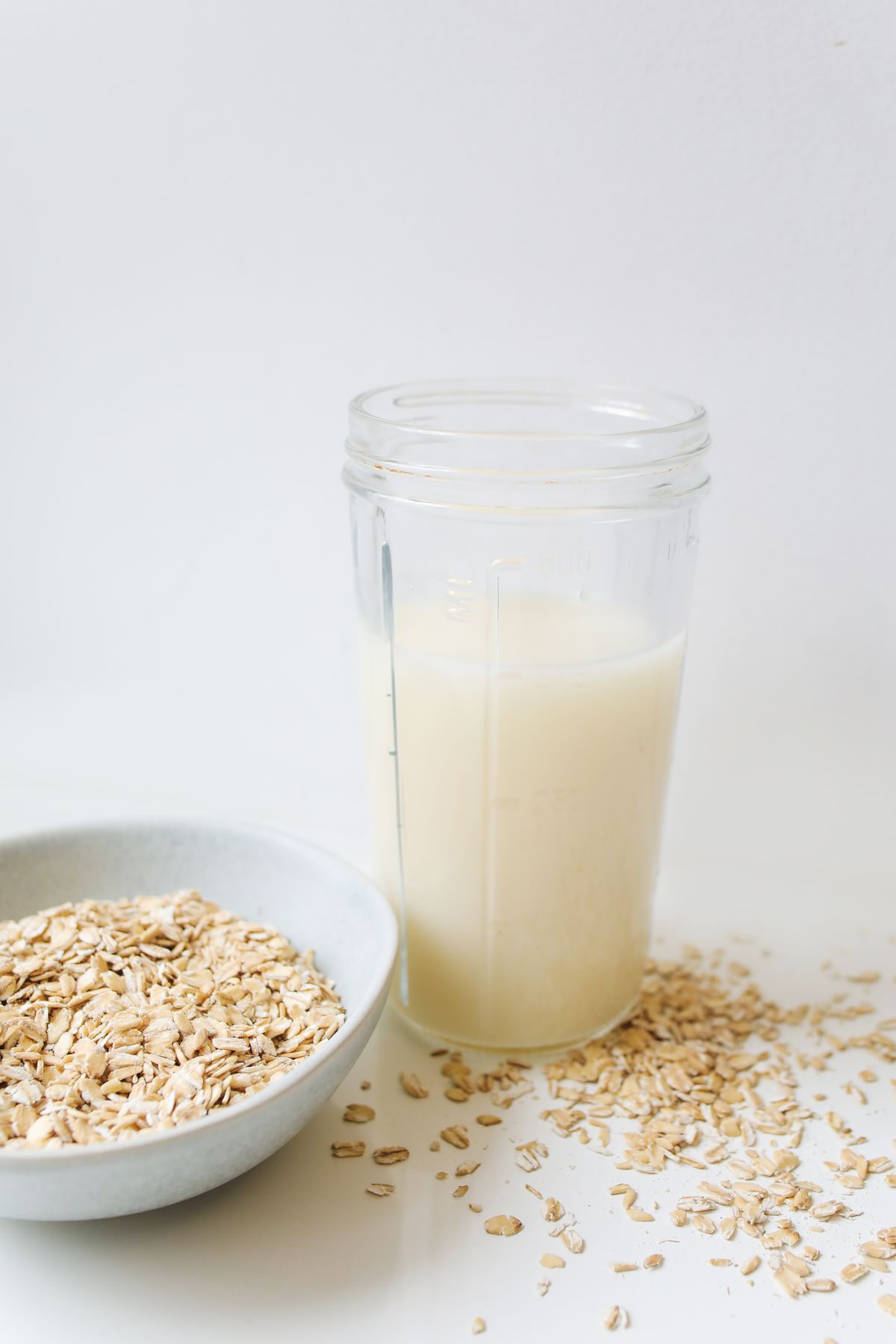 Oat drink in a clear jar beside oats