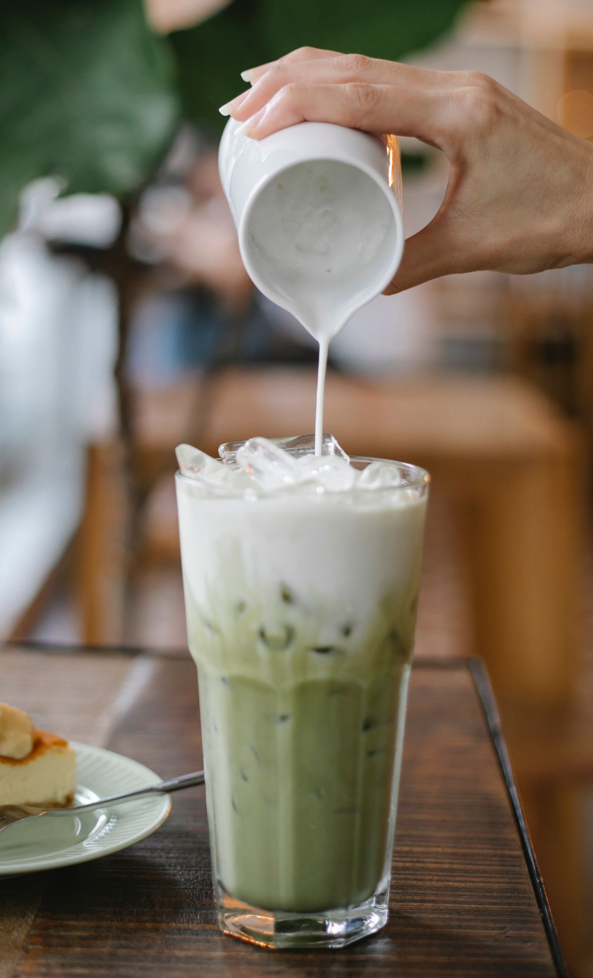 Milk being poured into an iced matcha latte